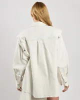 Chaqueta estilo camisa de algodón elástico color blanco, con mangas desmontables y botones. Costuras en contraste en toda la prenda y corte ligeramente oversize.