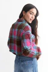 Buzo crop de corderito con estampado a cuadros en blanco, negro y rojo, con cierre de cremallera en el cuello.