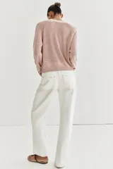 Sweater de punto color beige con cuello redondo, manga larga y cierre frontal parcial con botones. Presenta terminaciones en rib en cuello, puños y dobladillo.