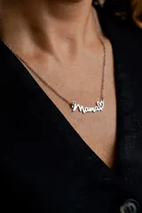 Collar de cadena fina con dije de la palabra 'Mamá' en tipografía cursiva, finalizado con un pequeño corazón. Fabricado en acero quirúrgico.