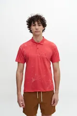 Chomba color coral con estampado de hojas blancas, cuello clásico con cartera de dos botones y logo bordado en el pecho.