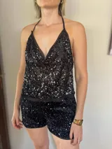 Top negro con lentejuelas, escote en V y tirantes finos. Espalda descubierta con lazos para regular.