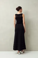 Falda larga negra de punto con silueta al cuerpo y leve evasé. Presenta transparencias lineales en el ruedo.