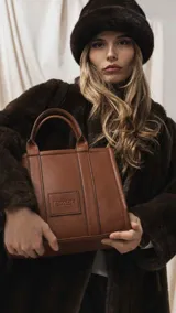 Cartera estructurada de tamaño mediano, confeccionada en símil cuero color negro. Presenta doble asa de mano, correa larga ajustable y desmontable, y un bolsillo trasero con cierre. El compartimento principal cuenta con cierre, división interna y bolsillos organizadores.