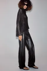 Camisa de hilatura con viscosa color negro, con cuello subido y manga larga ancha. Presenta aplicaciones de abalorios combinados a tono en toda la prenda y bajo recto.