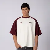 Remera estilo raglán color crudo con mangas y cuello en bordó, de manga corta, corte relajado y detalles estampados en el pecho.