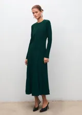 Vestido midi de corte evasé en color verde oscuro, con cuello redondo y mangas largas. Presenta un diseño con detalle de godets en la falda y cierre de cremallera en la parte posterior.