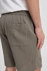 Bermuda de caída suelta con cintura elastizada y cordón regulable, confeccionada en tejido texturado negro.