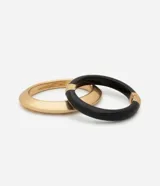Kit de dos brazaletes rígidos, uno de color negro y otro de color dorado, con diseño minimalista y estructura articulada.