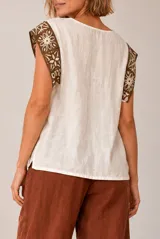 Blusa de lino color beige sin mangas, con cuello redondo y detalles de crochet en los hombros.