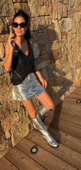 Bota alta plateada de cuero sintético con suela track negra, cierre lateral con cremallera y detalle de hebilla ajustable en el tobillo.