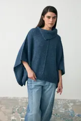 Capita de tejido de punto grueso en color azul, con cuello alto tipo polera y diseño asimétrico de corte holgado.