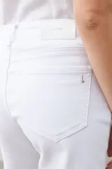 Bermuda de jean color blanco, con cinco bolsillos, corte a la rodilla y cierre frontal con botón y cremallera.