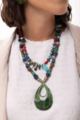 Collar corto de diseño artesanal compuesto por una variedad de cuentas de piedras naturales, cristales checos y acrílicos en tonos multicolor, incluyendo rojo, azul, turquesa y gris. Presenta un dije central en forma de gota color turquesa y cierre con cadena de acero quirúrgico ajustable.