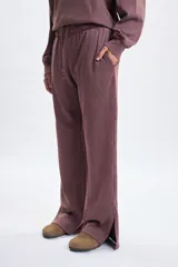 Pantalon deportivo de corte ancho y tiro medio, con efecto lavado en color marrón. Presenta aberturas laterales en el ruedo y cintura elástica con cordón de ajuste.