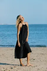 Vestido midi negro con cuello halter, lazada ajustable en el cuello y diseño fluido con espalda descubierta.