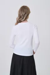 Remera de manga larga ajustada al cuerpo, color blanco, con cuello redondo bajo y tejido acanalado.