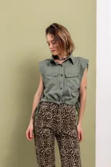 Camisa sin mangas color verde oliva, con cuello clásico, cierre frontal con botones, hombreras y cintura ajustable con cordones.