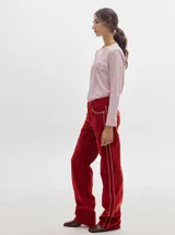 Pantalón de tiro medio confeccionado en pana color rojo, con corte holgado y detalle de línea lateral en contraste.