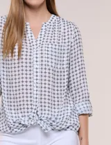 Blusa de gasa Zac & Rachel con estampado de rayas verticales en tonos rosados, amarillos y blancos. Presenta escote en V con cuello mao, cierre frontal con botones, un bolsillo aplicado en el pecho, mangas largas con presilla para regular el largo y detalle de nudo en el dobladillo inferior.