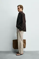 Pantalón relaxed fit para hombre, confeccionado en tejido con mezcla de algodón y lino, en color beige. Presenta bolsillos laterales, bolsillos traseros de plastrón y cierre frontal con cremallera y botón.