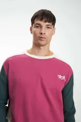 Buzo color crudo con mangas ranglan, puños y cintura acanalados. Presenta mangas color marrón y negro, y logo bordado con el número 1955 en el pecho.