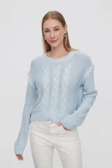 Sweater de punto color celeste, con diseño de trenzas frontales, cuello redondo y corte holgado.