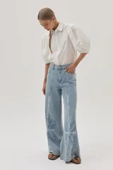 Jean de calce recto y tiro medio-alto, color celeste claro, con bordado a lo largo de la pierna.