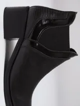 Bota tipo chelsea de caña baja, confeccionada en cuero con textura grabada efecto reptil en color marrón oscuro. Presenta paneles laterales elásticos en gamuza al tono y un taco cuadrado de altura media.