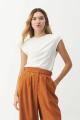 Remera blanca de algodón con elastano, de corte holgado y mangas cortas. Presenta un frunce drapeado en la parte delantera.