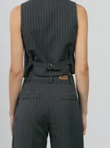 Chaleco sastrero gris con estampado a cuadros, escote en V y cierre frontal con botones.