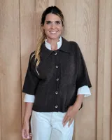 Cardigan de lana lambswool color marrón oscuro, con cuello camisero, cierre frontal de botones y mangas cortas con terminación en puño acanalado. Presenta dos bolsillos frontales y diseño de corte recto.
