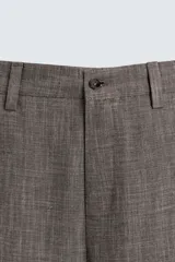 Pantalón de traje de corte slim fit, color marrón con textura sutil. Cuenta con cierre frontal de cremallera y botón, bolsillos laterales y bolsillos traseros de doble vivo con botón.