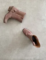 Bota estilo tejana de cuero vacuno color bordó, con detalle de argolla metálica y remaches decorativos.