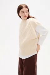 Chaleco de punto con diseño de ochos, cuello alto y corte holgado.