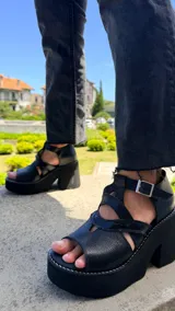 Sandalias de cuero color suela, con plataforma alta y taco ancho. Diseño con tiras cruzadas y apliques en texturas metalizadas y animal print, cierre con hebilla en el tobillo.