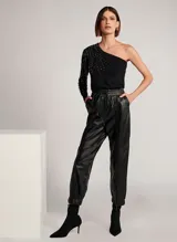 Pantalón jogger de cuero negro, con cintura elástica ajustable con cordón, bolsillos delanteros y traseros, bajos con elástico y aberturas de cremallera frontal.