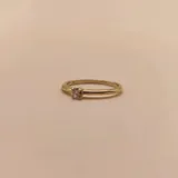 Anillo de oro 18k compuesto por una alianza fina con un brillante engastado y una estructura entrelazada de diseño moderno.