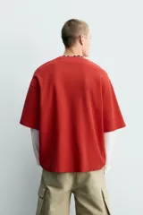 Camiseta relaxed fit de color rojo, cuello redondo y manga corta. Presenta estampados y bordados combinados a contraste en el delantero con inscripciones y el número 95.