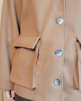 Sobrecamisa de paño color beige, con cuello solapa, cierre frontal de botones y dos bolsillos delanteros con solapa.