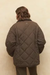 Campera capitoneada negra con botones veteados, bolsillos laterales de solapa y forro de satén con estampado animal print.