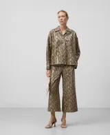 Sobrecamisa de poliuretano con estampado de piel de serpiente en tonos marrones y negros. Tiene cuello bowling, cierre con botones, manga larga con puños abotonados y forro de algodón.