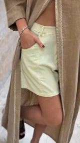 Short de lino en color celeste, con diseño de tiro alto, cierre frontal con botón a la vista y costuras decorativas verticales en el frente.