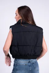 Chaleco puffer corto color blanco, con cuello elevado y cierre frontal. Cuenta con diseño acolchado y bolsillos laterales.