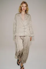 Blazer de estilo oriental confeccionado en hilatura de viscosa con tejido jacquard tono sobre tono. Presenta escote en pico, manga larga y cierre frontal cruzado con alamares a tono.