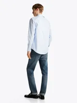 Camisa celeste de corte slim confeccionada en popelín de algodón con Flex Technology, cuello inglés, puños redondeados con botones y logo de Tommy Hilfiger bordado en el pecho.