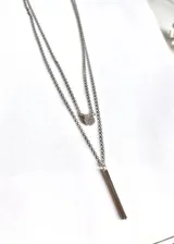 Collar plateado de doble cadena, con dije circular con circonitas y dije de barra vertical.