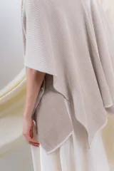Ruana tejida en punto acanalado, con diseño bicolor en tonos crudo y beige, de caída fluida y envolvente.