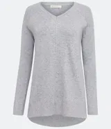 Blusa de punto color gris melange con escote en V y manga larga. Presenta un diseño con barra mullet, siendo más larga en la parte posterior, y está confeccionada en un tejido de punto suave de viscosa y poliamida.