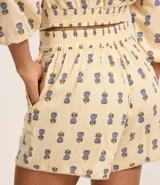 Short de tiro alto confeccionado en mezcla de viscosa y lino, con estampado de piñas pequeñas. Presenta bolsillos frontales redondeados y cintura con elástico en la parte posterior.